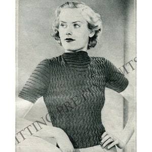 May include: A black and white vintage photo of a woman wearing a knitted sweater with a high neck and short sleeves.
