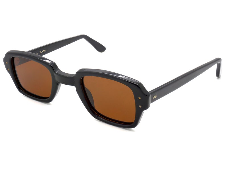 Puede incluir: Gafas de sol rectangulares negras con lentes marrones. Las gafas tienen un estilo cl&aacute;sico y retro.