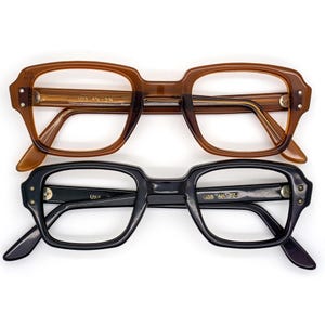 Puede incluir: Dos pares de gafas vintage. Un par tiene una montura marrón con el texto "USS 4 1/2 - 5 3/4". El otro par tiene una montura negra con el texto "USS 4 1/2-5 3/4". Ambos pares tienen forma rectangular.