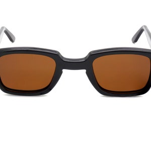 Puede incluir: Gafas de sol rectangulares negras con lentes marrones.