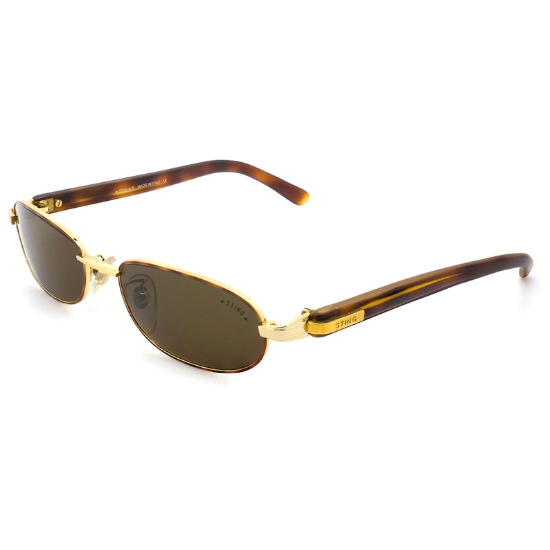 Puede incluir: Gafas de sol de carey marr&oacute;n con detalles dorados y lentes marrones. Las gafas tienen la palabra "STING" en el lateral.