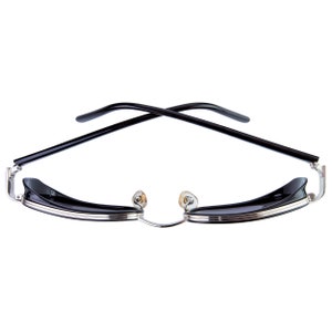 May include: Black sunglasses with a silver frame and black lenses. The arms of the sunglasses are crossed over each other.