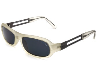 Könnte beinhalten: Rechteckige Sonnenbrille mit hellgrauem Rahmen und dunklen Gläsern. Die Bügel sind schwarz mit dem Markennamen "STING" auf der Seite. Die Sonnenbrille hat ein modernes, sportliches Design.