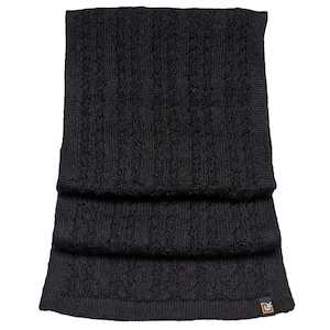 May include: Black knitted scarf with a textured pattern. The scarf is folded in thirds and has a small black tag with the letters "EK" on the bottom right corner.