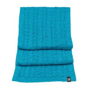 May include: A folded turquoise blue knitted scarf with a cable knit pattern. The scarf has a small orange tag with the word "Lif" on it.