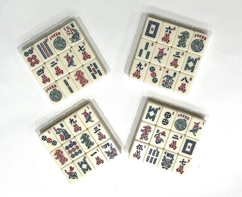 Op de afbeelding: Een set van 10 witte domino's met rode en zwarte markeringen. De domino's zijn gerangschikt in vier groepen van drie, met de resterende twee domino's aan de rechterkant van de afbeelding. De domino's hebben nummers en symbolen erop, waaronder het woord "JOKER".