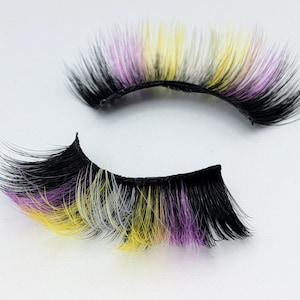 May include: A pair of false eyelashes with a black base and multi-colored tips. The tips are a mix of yellow, purple, and white, creating a vibrant and eye-catching effect. The lashes are designed to enhance the eyes.