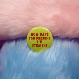 May include: A yellow button with the text "How dare you presume I'm straight" in red letters.