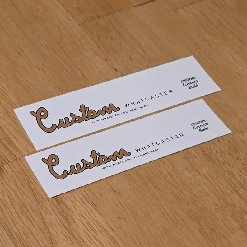 Puede incluir: Dos pegatinas rectangulares blancas con la palabra "Custom" en marr&oacute;n. Debajo, el texto dice "WHATCASTER" y "WITH WHATEVER YOU WANT HERE." La frase "ORIGINAL Custom Build" est&aacute; impresa en el lado derecho.