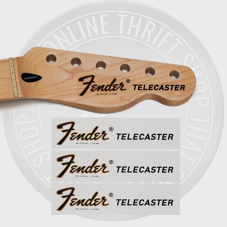 May include: A close-up of a light brown wooden guitar neck with a black Fender Telecaster logo. The neck has six tuning pegs and a black dot inlay. Three white stickers with the same logo are shown below the neck.