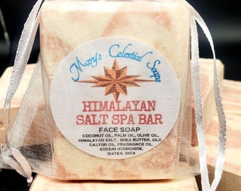 May include: A bar of Himalayan Salt Spa Bar face soap in a white organza bag. The soap is white and pink with a swirl pattern. The label reads "Mary's Celestial Soaps Himalayan Salt Spa Bar Face Soap Coconut Oil, Palm Oil, Olive Oil, Himalayan Salt, Shea Butter, Silk Castor Oil, Fragrance Oil, Sodium Hydroxide, Water, Mica."