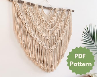 Op de afbeelding: Een beige macramé wandhanger met een houten lat aan de bovenkant. De hanger heeft een geometrisch patroon met franjes. De tekst "PDF Pattern" staat op een groene stervormige sticker.