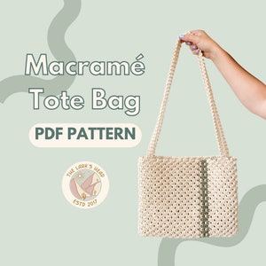 Peut inclure: Un sac cabas en macramé blanc avec une bande verte au centre. Le sac est tenu par une main. Le texte "Macramé Tote Bag PDF Pattern" est écrit en lettres noires grasses sur un fond vert clair. Un logo avec le texte "The Lark's Head Estd 2017" se trouve dans le coin inférieur gauche.