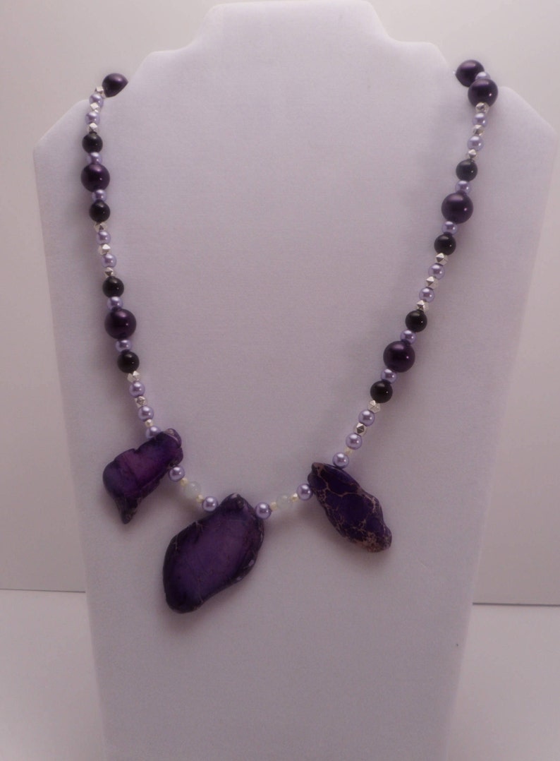 May include: A purple and silver beaded necklace with three purple agate pendant stones.