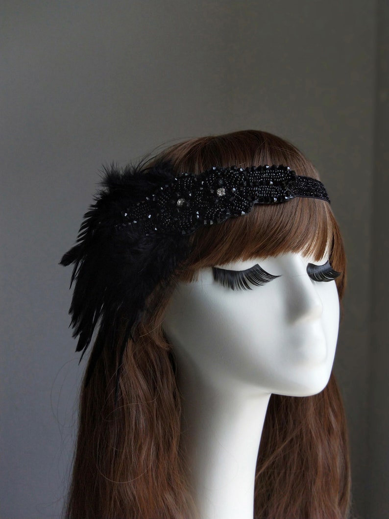 May include: A black headband with a feather and beaded embellishment. The headband is made of a soft, flexible material and is designed to fit comfortably on the head.