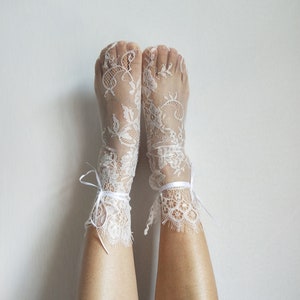 May include: White lace ankle socks with delicate floral patterns and white ribbon ties.