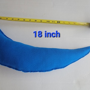 May include: A bright blue, crescent-shaped pillow, approximately 18 inches long, is displayed against a white background. A yellow measuring tape is placed next to the pillow, showing its length. The text "18 inch" is superimposed on the image.