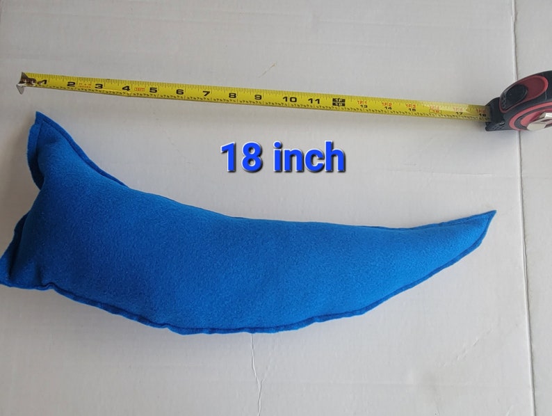 May include: A bright blue, crescent-shaped pillow, approximately 18 inches long, is displayed against a white background. A yellow measuring tape is placed next to the pillow, showing its length. The text "18 inch" is superimposed on the image.