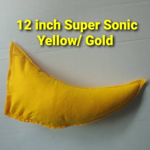 May include: A yellow, crescent-shaped pillow with the text "12 inch Super Sonic Yellow/ Gold" in yellow. The pillow is approximately 12 inches long and appears to be made of fabric.