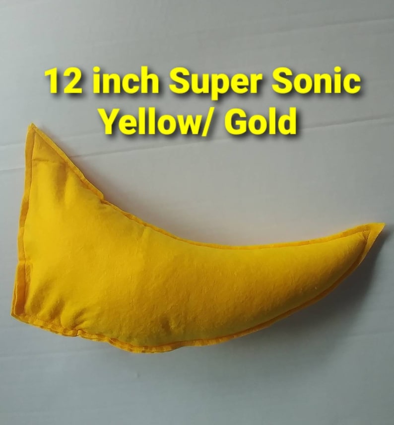 May include: A yellow, crescent-shaped pillow with the text "12 inch Super Sonic Yellow/ Gold" in yellow. The pillow is approximately 12 inches long and appears to be made of fabric.