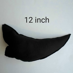 May include: A black, curved decorative pillow, approximately 12 inches in length. The pillow has a unique shape with a pointed end and a rounded base. The text "12 inch" is displayed above the pillow.