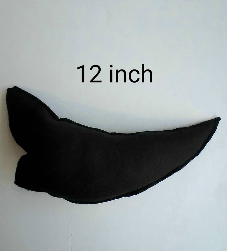 May include: A black, curved decorative pillow, approximately 12 inches in length. The pillow has a unique shape with a pointed end and a rounded base. The text "12 inch" is displayed above the pillow.
