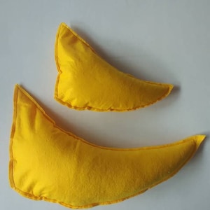May include: Two yellow crescent-shaped pillows. The pillows are made of a soft fabric and have a contrasting yellow trim. One pillow is larger than the other. The pillows are on a white background.