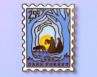May include: A gold-colored enamel pin shaped like a postage stamp with a blue and white design. The pin features a silhouette of two figures walking through a forest with a dog. The text "25¢ THE DARK FOREST" is printed on the pin.