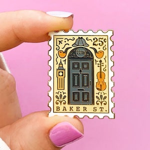May include: A gold-colored enamel pin shaped like a postage stamp with a black door, a clock tower, a violin, and the text "25c BAKER ST."