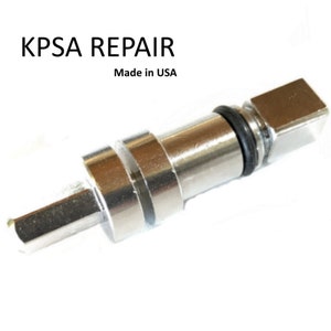 May include: A silver metal valve stem repair tool with a square head and a hex shaft. The tool is made in the USA.  KPSA REPAIR is printed on the image.