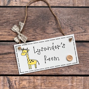 May include: White wooden sign with black text that reads "Lysander's Room". A cartoon giraffe is illustrated on the left side of the sign. A brown button is attached to the right side of the sign.