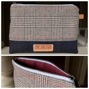 May include: A brown and white plaid zippered pouch with a black denim bottom and a brown leather patch that says "NEBO2 PDX-USA".