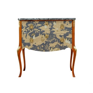May include: A two-drawer chest with a marble top and ornate gold accents. The drawers are covered in a blue and gold patterned fabric featuring a chinoiserie design.