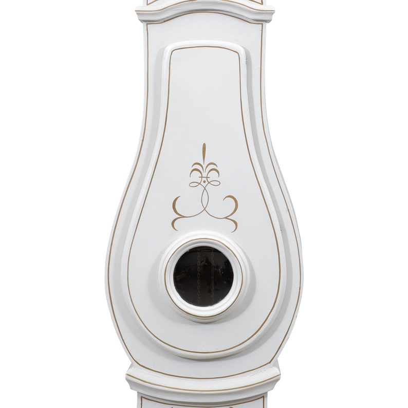 May include: White grandfather clock with a gold-painted design and a small, round, black clock face.