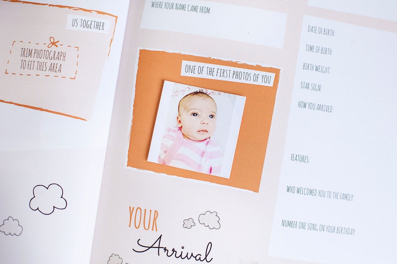 K&ouml;nnte beinhalten: Ein Baby-Erinnerungsbuch mit einem Foto eines kleinen M&auml;dchens in einem rosa-wei&szlig; gestreiften Outfit. Die Seite tr&auml;gt den Titel "Deine Ankunft" und enth&auml;lt Aufforderungen zur Aufzeichnung von Informationen &uuml;ber die Geburt des Babys, wie z. B. Datum, Uhrzeit, Gewicht und Sternzeichen.