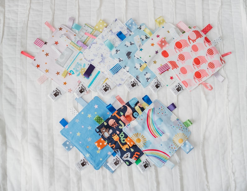 Puede incluir: Una colecci&oacute;n de diez mantas de etiquetas para beb&eacute;s de colores vivos con varios patrones, incluyendo estrellas, arco&iacute;ris, animales y dise&ntilde;os geom&eacute;tricos. Las mantas est&aacute;n hechas de tela suave y tienen cintas de sat&eacute;n atadas a las esquinas.
