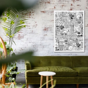 K&ouml;nnte beinhalten: Eine Schwarz-Wei&szlig;-Zeichnung einer Stadtlandschaft, gedruckt auf einem wei&szlig;en Poster, das an einer wei&szlig;en Backsteinwand &uuml;ber einem gr&uuml;nen Samtsofa und einem kleinen wei&szlig;en Holztisch h&auml;ngt.