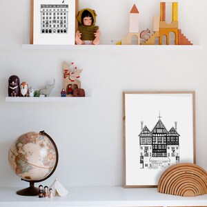 Puede incluir: Un estante blanco con dos ilustraciones en blanco y negro enmarcadas de edificios, un globo terr&aacute;queo y un juego de bloques de construcci&oacute;n de madera. El estante est&aacute; sobre un conjunto de tres cestas de mimbre.