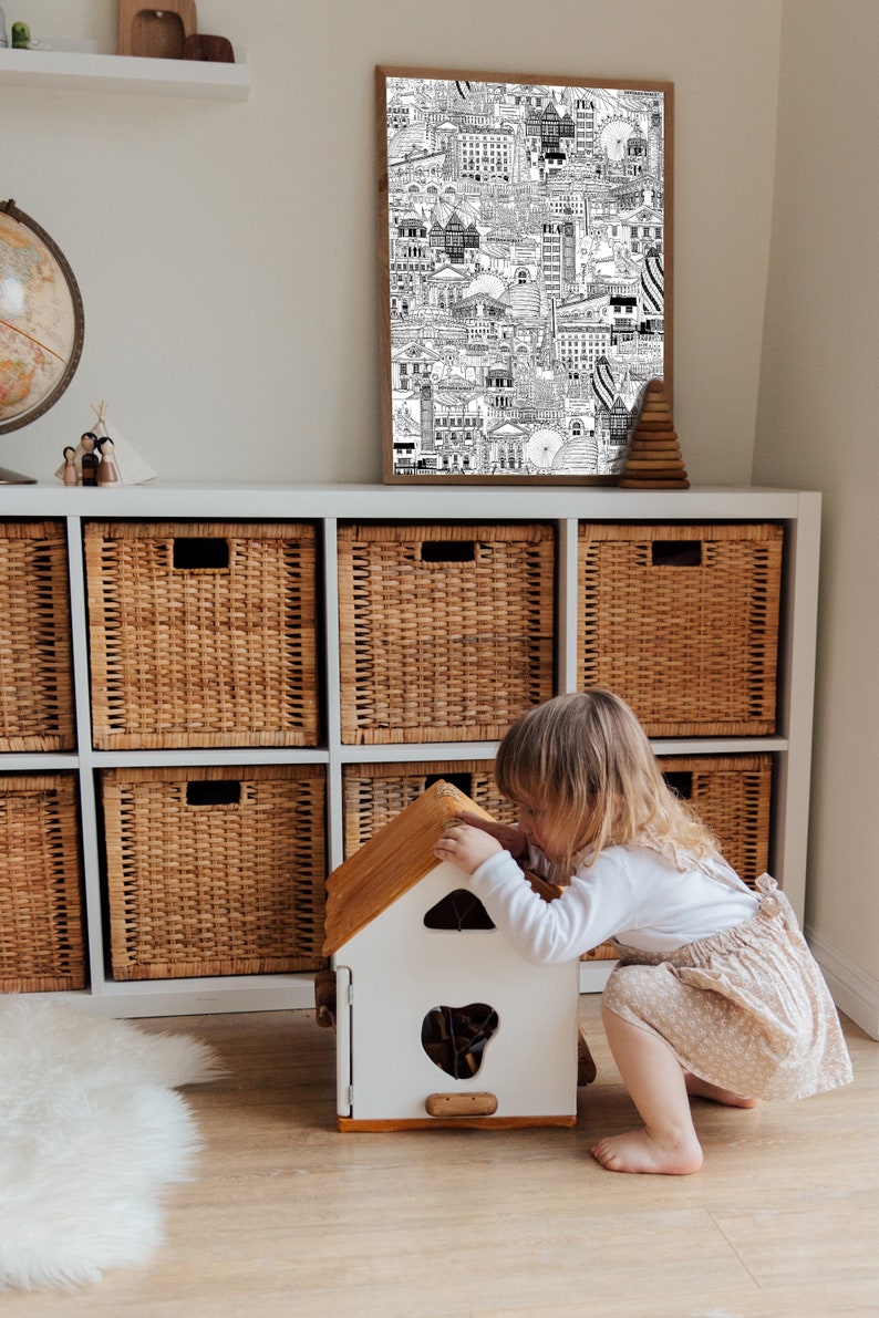 K&ouml;nnte beinhalten: Ein wei&szlig;es und braunes Holzspielzeughaus mit einem kleinen Fenster und einem braunen Dach. Ein kleines Kind spielt mit dem Spielzeughaus.