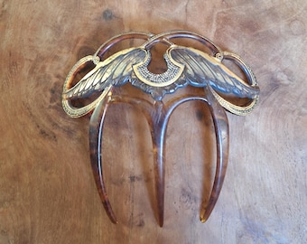 Bruine art nouveau haarkam met gouden versieringen in de vorm van uitgestrekte vleugels.