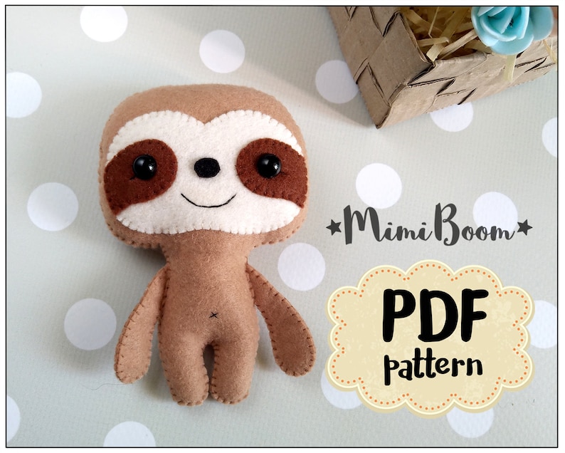 May include: A handmade felt sloth doll with a light brown body, white face, and brown accents. The sloth has black button eyes and a stitched smile. The image includes the text "Mimi Boom" and "PDF pattern".