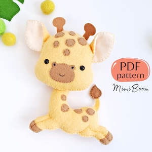 Könnte beinhalten: Ein Stofftier-Giraffe aus Filz mit braunen Flecken und einer hellbraunen Nase. Die Giraffe rennt und hat einen weißen Hintergrund. Der Text "PDF pattern Mimi Boom" befindet sich in der unteren rechten Ecke des Bildes.