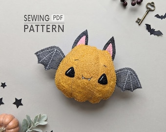 May include: A plush bat-pumpkin hybrid toy made of mustard yellow textured fabric with grey felt wings, black triangular eyes, and small white fangs. The text SEWING PDF PATTERN is visible. Decorative elements include a key, stars, and a small pumpkin.