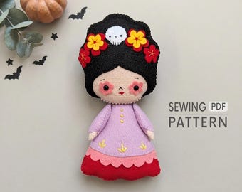 May include: A felt doll with black hair, a white skull accent, and yellow and red flowers. The doll wears a light purple dress with yellow embroidery over a red skirt. The text SEWING PDF PATTERN is visible on the right side of the image.