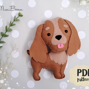 May include: A handmade felt dog in shades of brown and tan, with a pink tongue and black eyes. The dog has long, floppy ears and a small tail. The image includes the text "MimiBoom" and "PDF pattern".
