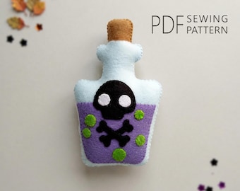 Puede incluir: Una manualidad de fieltro con forma de frasco de poción, con tapón color canela, parte superior azul claro y cuerpo morado con un aplique de calavera y tibias negras, puntos verdes y el texto PDF SEWING PATTERN en la esquina superior.