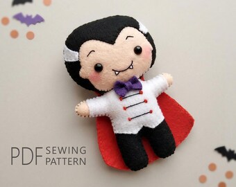 May include: A felt vampire doll featuring black hair, a white jacket with red accents, a purple bow tie, and a red cape. The doll has black eyes, pink cheeks, and two small white fangs. The text PDF SEWING PATTERN is printed in the lower left corner.