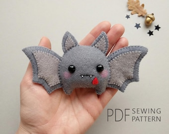 May include: A gray felt bat plush toy with light gray inner wings and ears, black bead eyes, pink cheeks, two small white fangs, and a red tongue. The text PDF SEWING PATTERN is printed in the bottom right corner of the image.