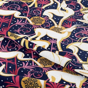 May include: A navy blue fabric with a repeating pattern of white stylized deer, pink and yellow stylized palm trees, and gold stylized snowflakes. The background is a dark blue with white dots.