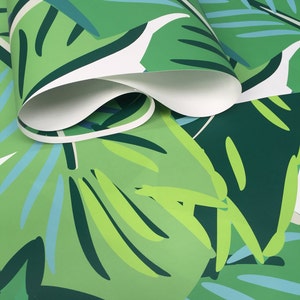 May include: Green and blue tropical leaf patterned wallpaper. The wallpaper is rolled up and shows the pattern repeating.